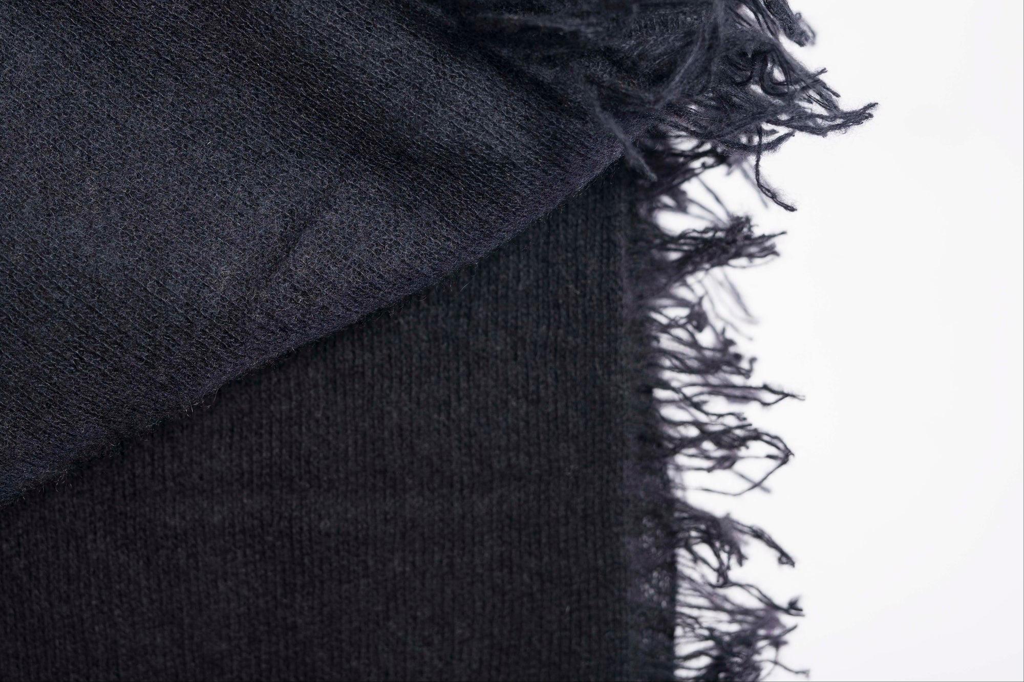 Close-up of a dark gray blanket with frayed edges on a white background